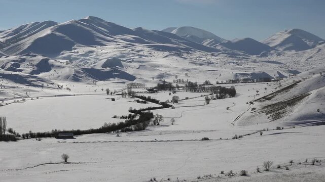 Snowy winter landscape in rural Anatolia Turkey with mountains plains and village scenery. Cold season countryside creates a calm background across snowy mountain plains and villages.