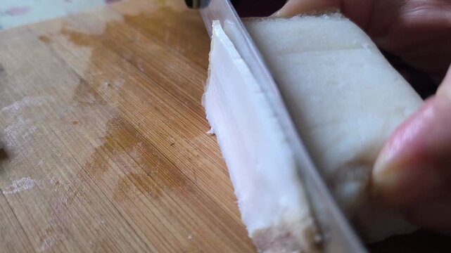 Cooking at home, pancetta - smoked bacon cut using sharp kitchen knife