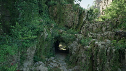 A dense, vibrant cave entrance beckons with thick greenery and rocky landscapes. Sunlight filters through, highlighting the beauty of this hidden natural wonder.