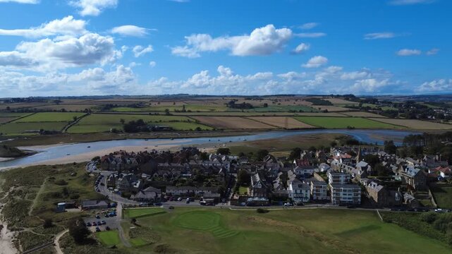Aerial drone view of the village of Alnmouth in Northumberland in summer showing buildings and roads along the river Aln and surrounding countryside