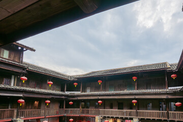 Naklejka premium Fujian Yongding Tulou are circular earthen homes with red lanterns, over a century old, inhabited, preserved, UNESCO-listed amid scenic mountains and rivers.