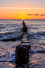 Fototapeta premium Golden Sunset over Wooden Groynes on the Baltic Sea Coast