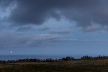 Fototapeta premium A cloudy sky with a bright red moon in the background