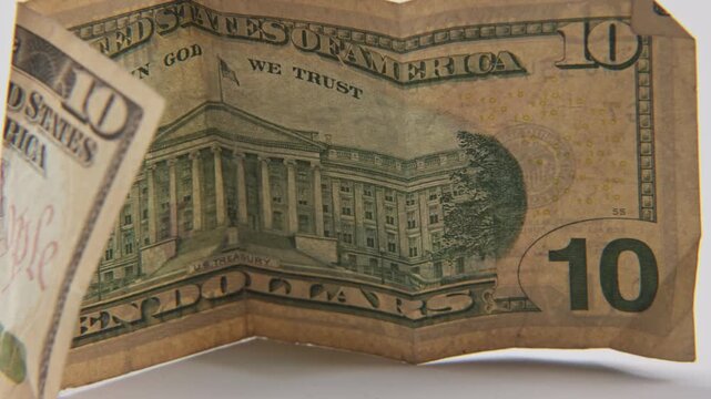Alexander Hamilton the first U.S. Secretary of the Treasury portrait on printed ten 10 dollar bill of United States of America cash and printed treasury bills in close up and studio slo mo slow motion