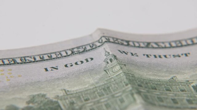 Printed text of In God We Trust on paper money dollar bill of high value and American economy from United States printed cash bills on close up surface of print texture and USA government building