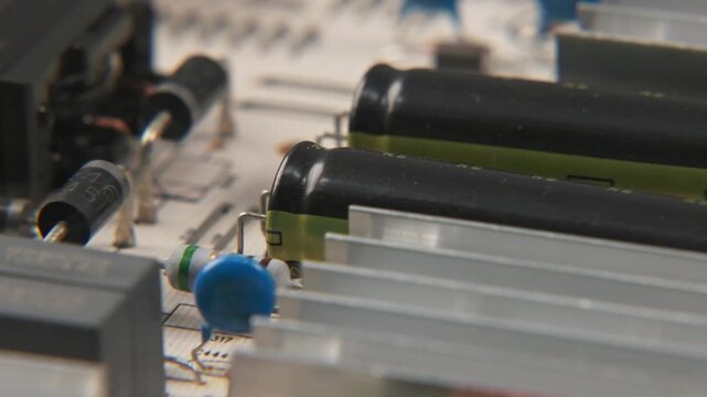 Close up slow motion of TV television video power supply electronic electronics board for internal media with transisteos, transformers, heat sink, and small wires and cables attached to inside device