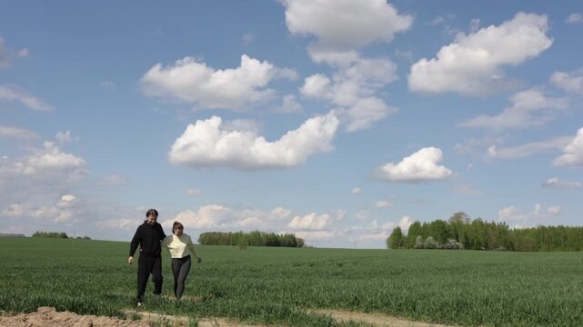 a loving couple walking through a field in summer