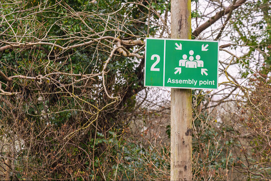 Emergency assembly point sign mounted on wooden post outdoors