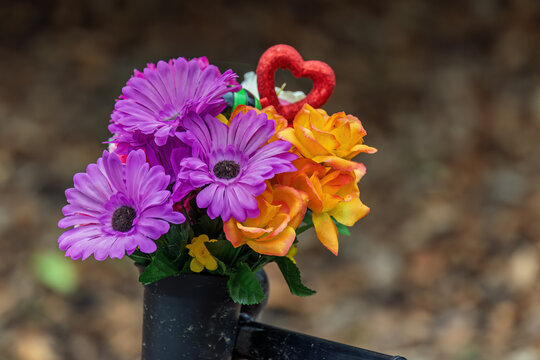 Artificial flowers tribute attached to memorial bench outdoors