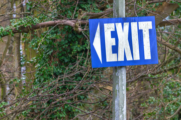 Blue exit sign with arrow mounted on pole outdoors