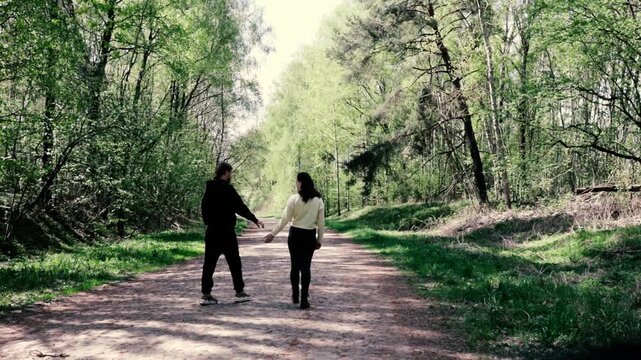 a young couple walking along a road in a spring forest