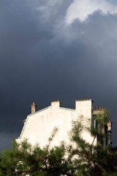 Storm clouds and sky frame urban building silhouette as minimal architecture with sunlight and strong contrast for dramatic outdoor background scene