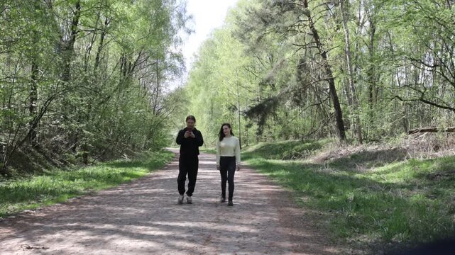 a young couple walking along a road in a spring forest