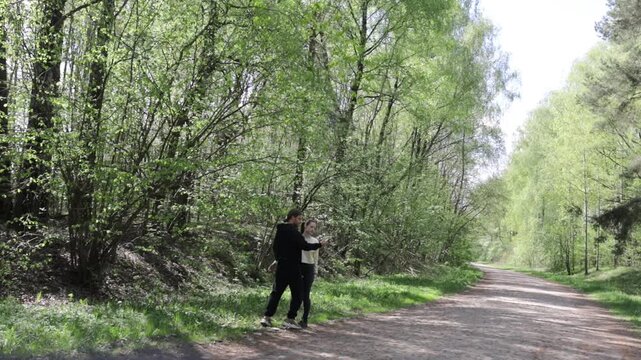a young couple walking along a road in a spring forest