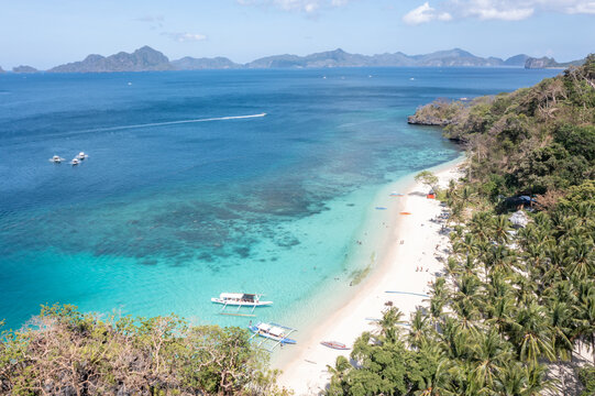 Drone top-down composition of Seven Commandos Beach with tourists swimming and boats offshore