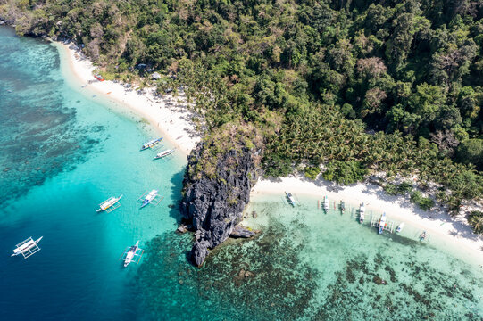 High altitude aerial view of Papaya Beach and Seven Commandos Beach with boats and crystal clear waters in El Nido