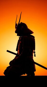 Silhouette of a kneeling samurai warrior in traditional armor with a katana sword against a vibrant orange and yellow gradient sunset sky