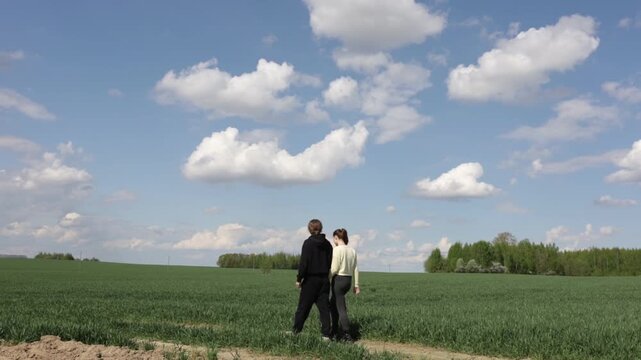 a loving couple walking through a field in summer