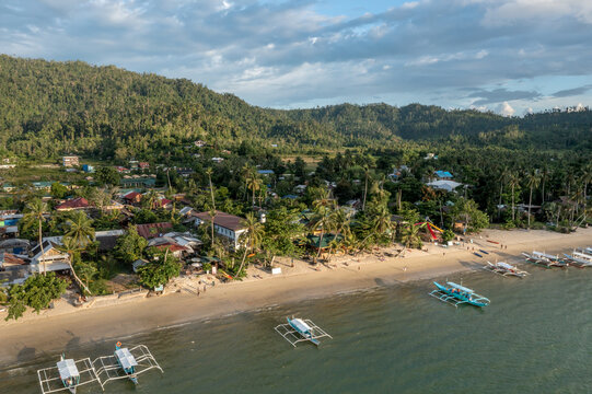 Aaerial coastline with traditional banca boats on tropical white sand beach and lush forest Port Barton Palawan