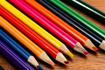 Fototapeta premium Macro Close-up of Vibrant Colored Pencils Arranged Diagonally on Wooden Table, Colorful Stationery and Art Supplies Background with Shallow Depth of Field