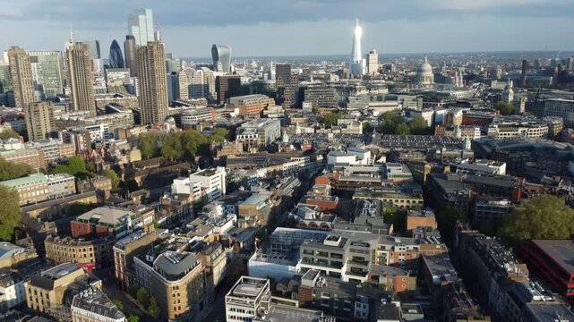 Aerial perspective from Clerkenwell over London, featuring the Barbican Estate, City skyscrapers, The Shard, and St Pauls Cathedral.