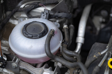 Fototapeta premium Detailed view of a car coolant expansion tank with pink antifreeze liquid under the hood of a modern vehicle. Automotive maintenance, engine cooling system and car service parts