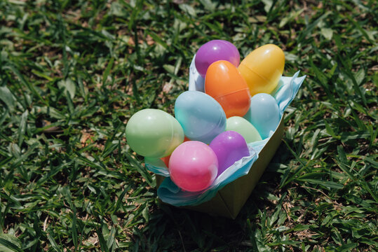 Happy Easter colorful eggs in basket on lawn grass during sunny spring outdoor celebration.