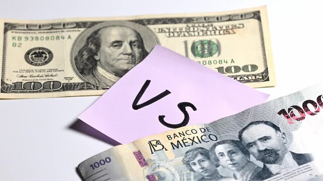Money concept, one hundred dollar bill against a one thousand peso Mexican bill, with a sticky note with the letters VS in between