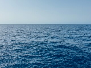 The endless sea in calm weather and clear sky on a blue background.