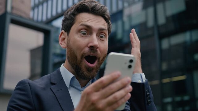 Caucasian man amazed happy businessman look mobile phone message good news win male using smartphone gadget success business shocked employer office guy developer entrepreneur internet city outdoors