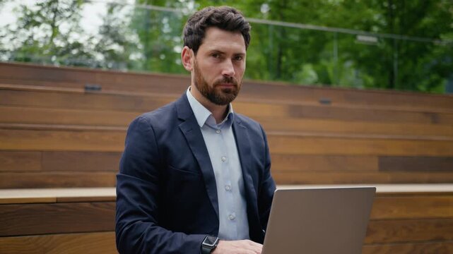 Caucasian businessman smiling looking at camera working laptop outdoors in city guy middle-aged entrepreneur business man employer freelancer online male architect real estate agent typing computer