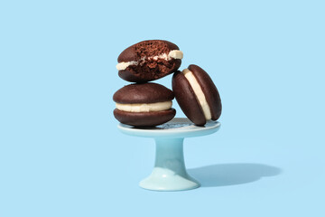 Stand with chocolate whoopie pies on blue background