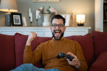 Fototapeta premium Excited man playing video game winning and cheering