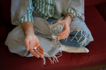Person taking medication holding pill and water glass