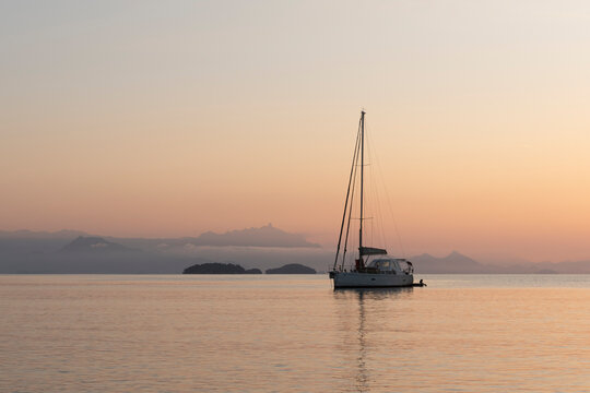 View of calm sea during sunrise with boat against islands