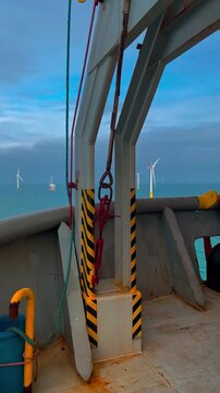 Industrial ship deck with safety features. Closeup of safety lines and hazard stripes on shipping vessel with turbines in background