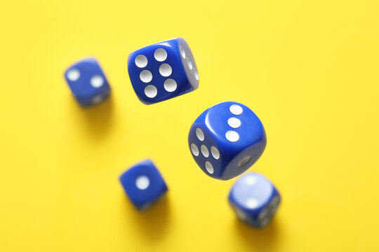 Flying blue game dices on yellow background