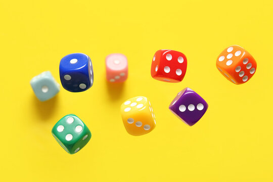 Flying colorful game dices on yellow background