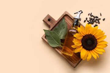 Bottle of oil with sunflower, leaves and seeds on beige background