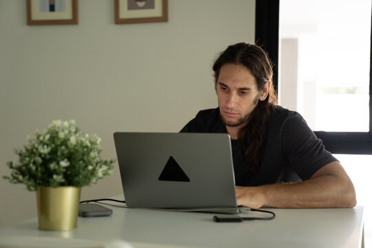 Man working remotely on laptop at home office desk