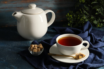 Fototapeta premium Composition with teapot and cup of black tea on blue grunge background, closeup