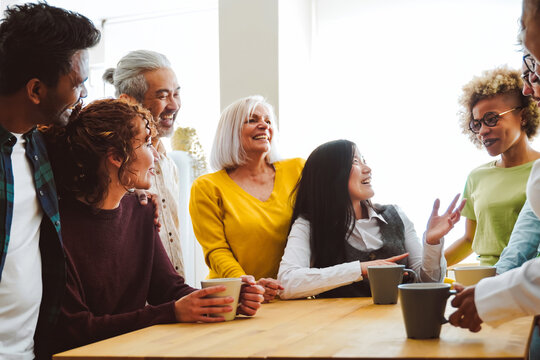 Group of multiracial friends with different ages and ethnicities have fun in coffee break at home kitchen - Focus on left girl face