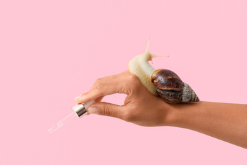 Female hands, snail and dropper with serum on pink background © Pixel-Shot