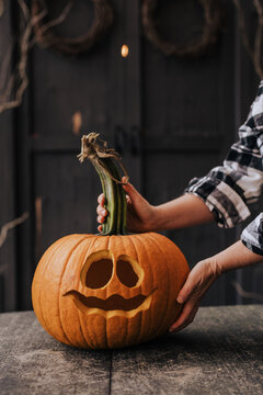 A woman carving a pumpkin for a halloween party decoration in October.
