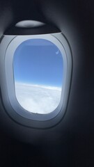 Fototapeta premium Vue a travers un hublot d'avion au dessus des nuages