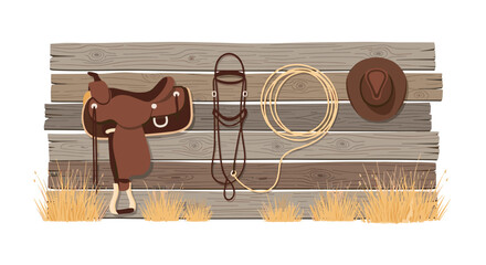 Fototapeta premium A brown leather saddle and a coiled rope hang alongside a bridle and a cowboy hat on a weathered wooden fence above patches of dry grass.