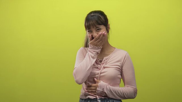 Young woman laughing with hand on stomach, covering her mouth in moments of giggles against a lime green studio backdrop showing sequential smiles; joy.