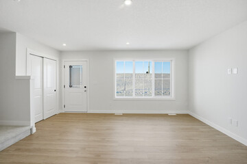 Large, empty living room with a white door and a window
