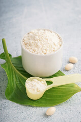 Cup and scoop of collagen powder and pills on white grunge background