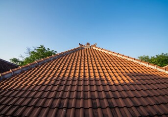 Terracotta tiled roof of a Balinese house against a clear blue sky